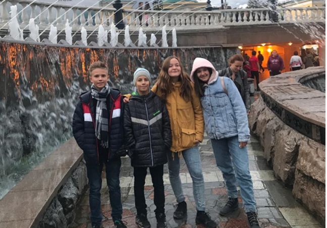 Zwei Jungen und zwei Mädchen posieren vor einem Brunnen in Moskau