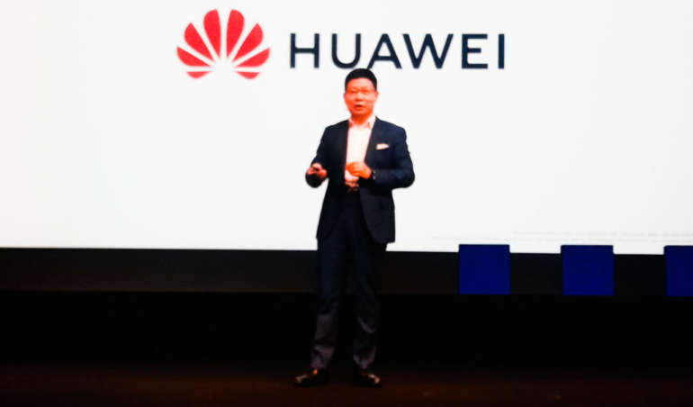 Ein Mann steht vor einer Leinwand mit dem Huawei-Logo.