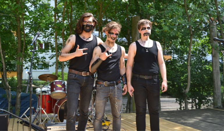 Herders Heavy-Metal-Band steht auf einer Bühne in Kostümen und mit Musikinstrumenten