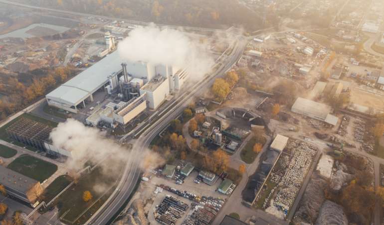 Aus einem Kraftwerk steigt Rauch auf. Eine Ansicht aus der Vogelperspektive über eine Stadt.