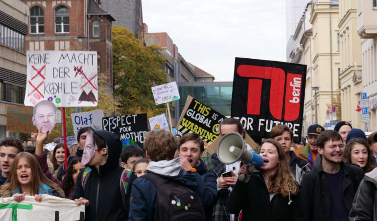 Luisa Neubauer steht in einer Gruppe Demonstrant*innen mit einem Megaphon