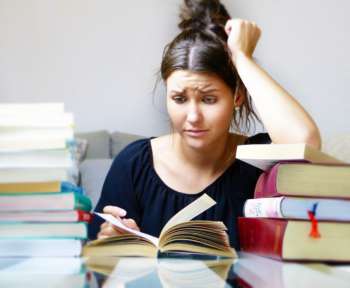 Ein Mädchen schaut genervt in ein Schulbuch. In etwa so stellt man sich Unterricht während der Sommerferien vor.