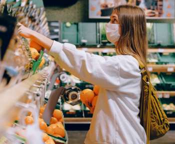 Frau kauft Obst und greift zur Plastiktüte
