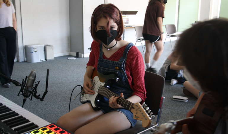 Schülerin spielt die Gitarre während einer Aufzeichnung